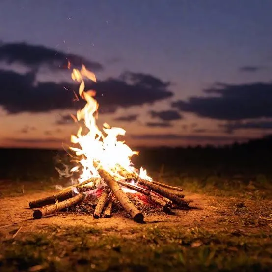 A campfire glowing under the evening sky